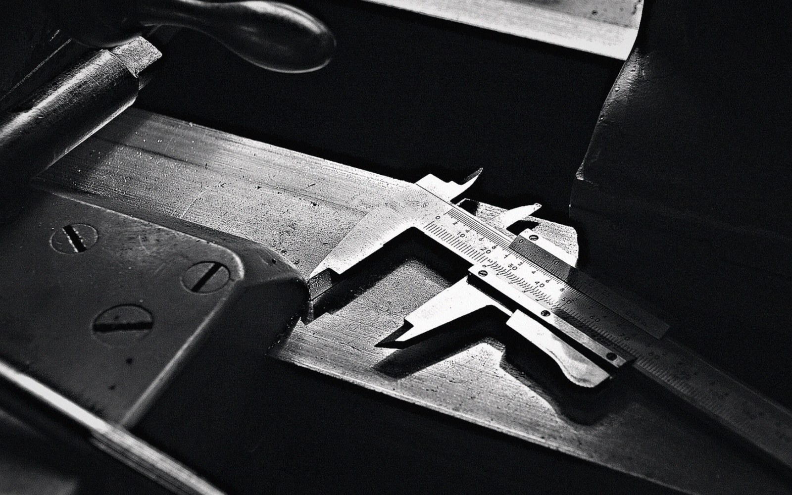 A metal vernier caliper resting on a workbench beside old machinery parts
