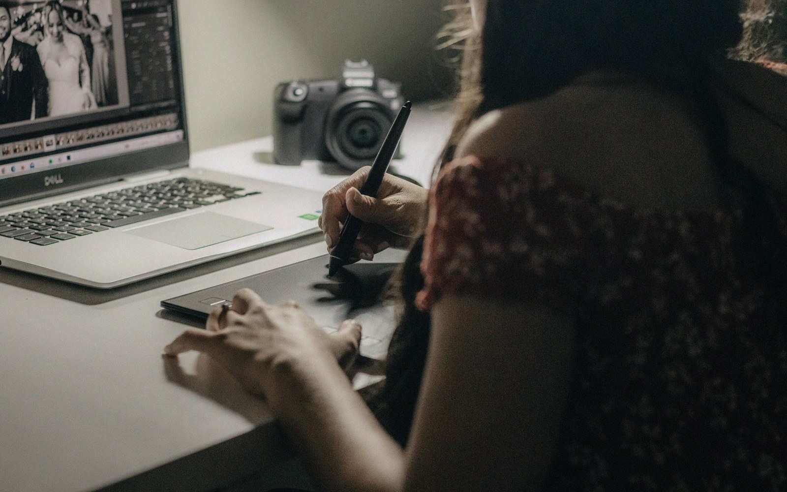 Photographer editing wedding photos on a laptop using a graphics tablet and pen